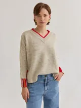 Buzo de lana color beige con escote en V y mangas de rayas, de fit holgado y suelto.