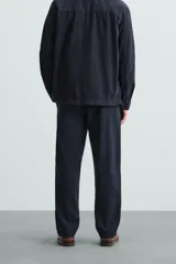 Pantalón azul marino de corte recto, confeccionado en tejido de algodón y lino. Tiene cintura elástica ajustable con cordón, bolsillos delanteros y traseros de vivo.