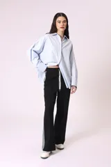 Camisa celeste de corte amplio, con cuello clásico, cierre frontal con botones y bolsillo en el pecho.