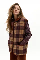 Chaleco oversized de paño de lana con estampado de cuadros en tonos beige, marrón y bordó. Presenta cuello y vivos en corduroy color caramelo, bolsillos plaqué frontales y cierre con botones a presión escondidos.