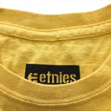 Remera color mostaza con logo de la marca Etnies estampado en el pecho.