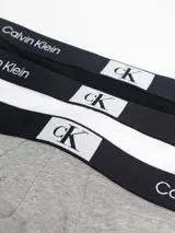 Pack de tres slips Calvin Klein en colores negro, blanco y gris, con cintura elástica negra con logo de la marca.
