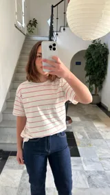 Camiseta blanca con rayas horizontales rojas y logo bordado en el pecho.