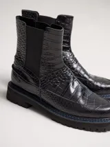 Bota Chelsea de cuero negro con estampado de cocodrilo, elástico lateral y suela de goma con pespuntes azules.