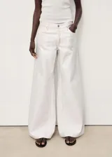 Pantalón de jean blanco de corte wide leg, tiro bajo, con cierre de cremallera y botón, y cinco bolsillos.
