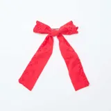 Pinza para el pelo con lazo rojo de tela bordada con pequeños orificios.