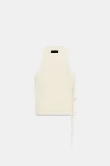 Chaleco color crema de punto, con escote en pico y sin mangas. Cierre cruzado frontal con lazada lateral.