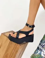 Sandalias negras con plataforma, tiras cruzadas y tobillera con hebilla.