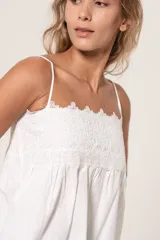 Blusa blanca con tirantes finos y escote recto con detalle de encaje.