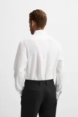 Camisa blanca de corte regular, cuello italiano, manga larga con puños abotonados y cierre frontal con botones.
