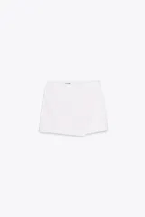 Falda pantalón blanca de tiro medio con diseño asimétrico.