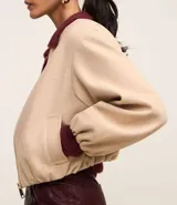 Campera bomber color beige con cuello y puños en color borgoña. Cierre frontal con cremallera y bolsillos laterales.