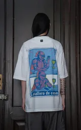 Remera blanca de algodón con cuello redondo y calce oversize. Estampado con diseño de dos caballeros medievales con armadura y capa roja, uno usando un celular y otro con una copa.