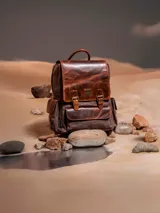 Mochila de lona color marrón con detalles en cuero color marrón oscuro. Tiene un compartimento principal con cierre de cremallera y solapa con broche imantado, bolsillo acolchado interior para laptop de 15", bolsillo interior con cierre, un bolsillo frontal con cierre, bolsillos laterales, pasador en la parte de atrás para maleta, bolsillo trasero con cierre cremallera, correas ajustables y forro interior con diseño Star Wars.