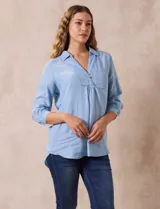 Blusa celeste de lyocell, con cuello con solapa, escote en V y abertura con botones. Mangas ¾ con puño y botón.