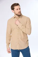 Camisa de lino color beige, de manga larga, con cuello clásico y bolsillo en el pecho.