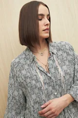Camisa marrón con estampado animal print negro, de calce relajado, cuello clásico, abotonadura frontal y mangas largas con puños camiseros.