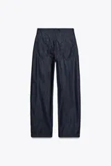 Pantalón de jean azul oscuro, de tiro alto, corte ancho y largo hasta el tobillo.