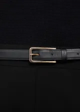 Mono largo negro con cuello redondo, sin mangas, trabillas y cinturón con hebilla.