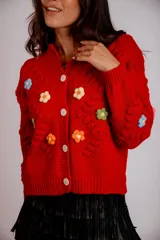 Saco color crema de tejido de punto con flores bordadas y cierre frontal con botones.