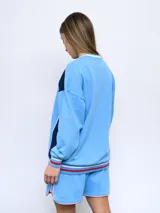 Buzo de felpa azul marino con mangas raglán rojas y detalles tricolor en puños, mangas y cuello. Incluye logo de Umbro bordado en el pecho y escudo del Club Nacional de Football.