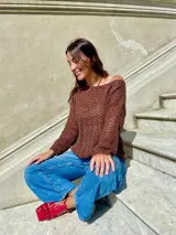 Sweater de punto calado color crema, con cuello, puños y ruedo en marrón con lurex. El cuello puede usarse de dos formas: mostrando un hombro o de forma clásica.