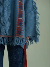 Sweater negro oversize de lana con cuello redondo, bordado central en forma de trenza, laterales con cuadrillé y mangas acampanadas desflecadas.