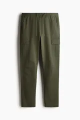 Pantalón cargo verde oliva de corte slim fit, confeccionado en tejido de algodón. Cuenta con cintura elástica ajustable con cordón, bolsillos laterales, bolsillos cargo con solapa y botón a presión en los muslos, y bolsillos traseros con solapa y botón a presión. Presenta costuras y pinzas en las rodillas.