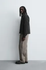 Sobrecamisa de denim de algodón negro con efecto lavado, corte relajado (relaxed fit). Presenta cuello solapa, cierre frontal con cremallera, manga larga con puño abotonado y bolsillo plastrón en el pecho.