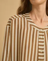 Vestido largo de manga larga con botones en el escote y tajos verticales laterales. Diseño a rayas verticales en tonos marrón y blanco.
