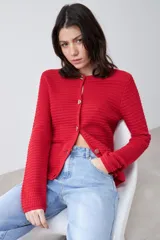 Chaqueta tejida roja con botones metálicos dorados y cuello redondo.