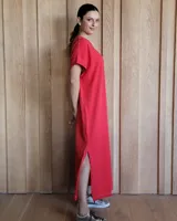 Vestido largo color crudo con cuello redondo y mangas cortas con ribete negro. Tiene corte recto y aberturas laterales en el ruedo.