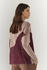 Buzo de punto con diseño geométrico en bloques de color gris y negro, de cuello redondo y mangas largas.