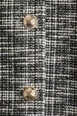 Chaleco cropped de punto bouclé a cuadros blancos, negros y grises, con cuello redondo, pinzas en el busto y botones dorados a presión.