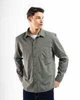 Camisa de manga larga color verde oliva, confeccionada en algodón. Tiene corte clásico, bolsillo en el lado izquierdo del pecho y cierre con botones.