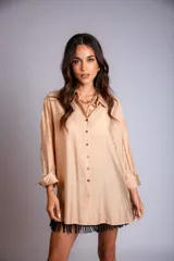 Camisa de corte holgado color beige, con detalles bordados en las mangas y flecos en la parte inferior.