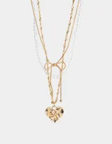 Collar dorado de tres capas: una de perlas, una de cadena de eslabones y una de cadena retorcida con dije de corazón con rosa grabada y moño.