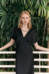 Vestido midi negro satinado con escote pico, pliegues en el busto y mangas cortas. Cintura entallada y cierre lateral con cremallera oculta.