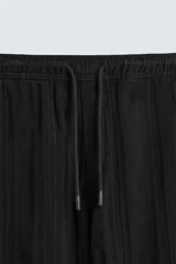 Pantalón verde oscuro de algodón con textura, corte recto, cintura elástica ajustable con cordón, bolsillos laterales y traseros de vivo.