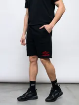 Bermuda deportiva negra de felpa con logo de Umbro bordado en rojo en la pierna derecha.