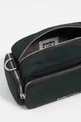 Bolso bandolera de nylon color verde oscuro, con estructura blanda y múltiples compartimentos con cierre de cremallera. Presenta correa ajustable de tejido negro y logo metálico con el texto "BIMBA Y LOLA" en blanco en el frente.