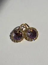 Par de aros colgantes con dije circular de resina con glitter multicolor y borde de strass. El arito es de acero quirúrgico dorado.