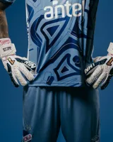 Short de arquero de fútbol Umbro del Club Nacional de Football, modelo Oficial 2025. Diseño celeste con detalles geométricos en azul y blanco. Incluye logo de Umbro y escudo del club.