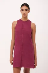 Vestido corto color fucsia de lino italiano, con cuello redondo y sisas desflecadas. Presenta detalle de desflecado a lo largo del vestido.