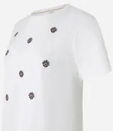Remera de manga corta color blanco, con cuello redondo y bordados de flores en el frente.