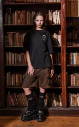 Remera negra de manga corta con cuello redondo y calce oversize. Presenta una estampa en la espalda inspirada en el tarot, con la carta "La Fuerza" que muestra a una mujer desnuda sobre un leopardo, rodeada de vegetación y un sol rojo.