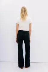 Pantalón jean de tiro medio, calce ajustado, con proceso de coating de acabado símil cuero y pierna levemente acampanada.