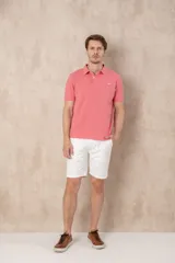 Chomba azul marino de piqué con cuello clásico, tapeta de dos botones y logo de pájaro bordado en color rosa en el pecho.