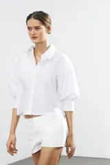 Camisa rosada de popelina de algodón, con cuello clásico, manga corta abullonada y cierre frontal con botones.