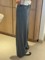 Pantalón ancho color verde oliva, de tiro alto y corte holgado. Confeccionado en mezcla de algodón y lino, con pinzas debajo de la rodilla, bordado de monograma en el bolsillo delantero y pespuntes a contratono.